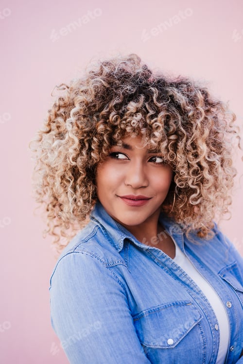 Preview: portrait of confident curvy hispanic woman outdoors in spring. pink wall. Body positivity