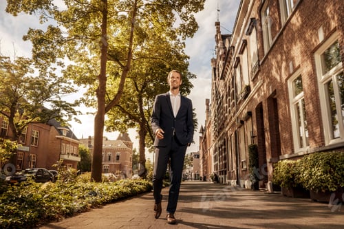 Preview: Netherlands, Venlo, confident businessman walking on pavement