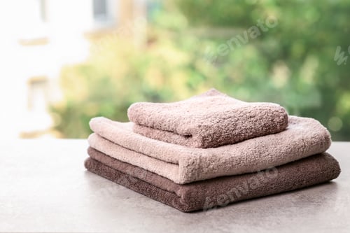 Preview: Stack of clean towels on table against blurred background. Space for text
