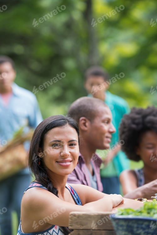 Preview: A group of adults and young people at a meal in the garden of a farmhouse.