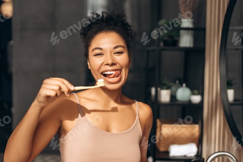 Preview: Young woman brushing teeth with toothbrush and toothpaste in bathroom