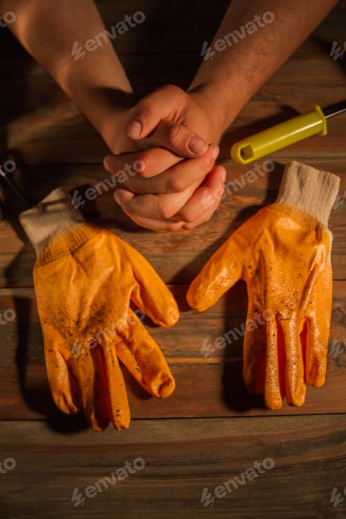 Preview: Dirty worker's gloves and hands crossed.
