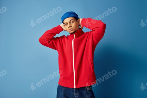 Preview: Trendy young Black man poses confidently against a blue backdrop