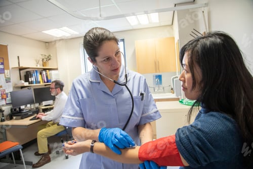 Preview: Nurse examining a patient's arm for blood pressure and pulse