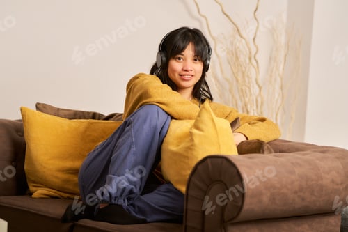 Preview: young asian girl sitting relaxed enjoying some free time listening to music at home