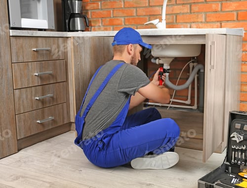 Preview: Professional plumber in uniform fixing kitchen sink