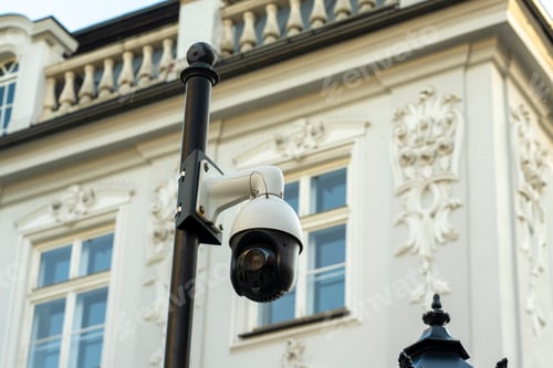 Preview: Security camera mounted on a pole in front of an elegant building with intricate architectural