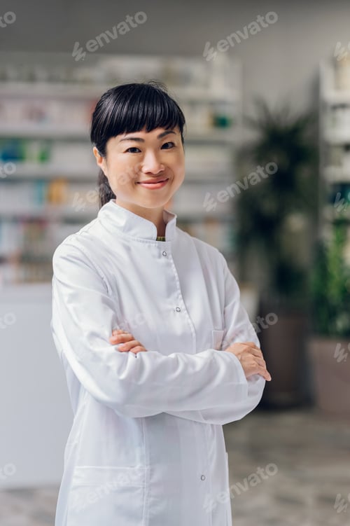 Preview: Portrait of a happy Japanese apothecary worker standing with arms crossed and smiling at the camera.