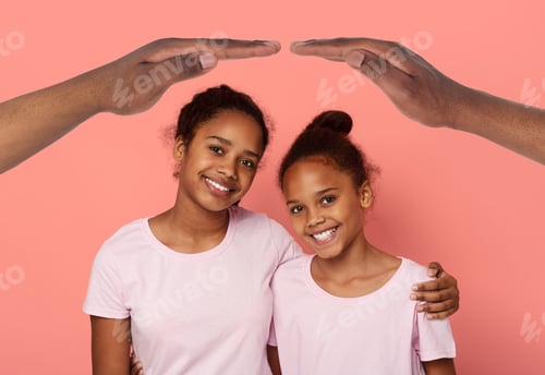 Preview: Cute african american girls sisters hugging under hands roof
