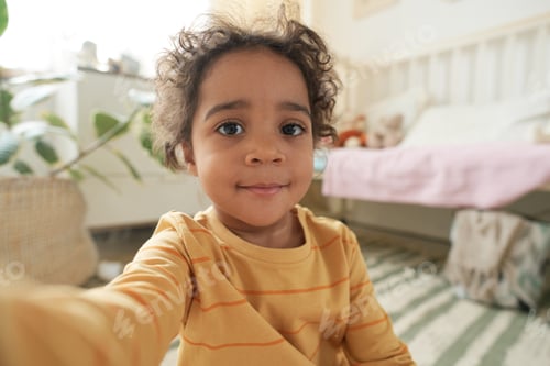 Preview: Smiling Child Sitting in Cozy Bedroom with Potted Plant