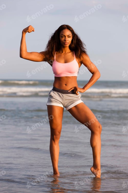 Preview: Young woman on beach, flexing muscles, posing
