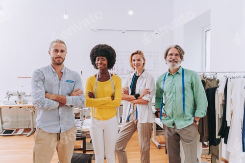 Preview: Smiling Designers Standing in Bright Workshop with Sewing Machines