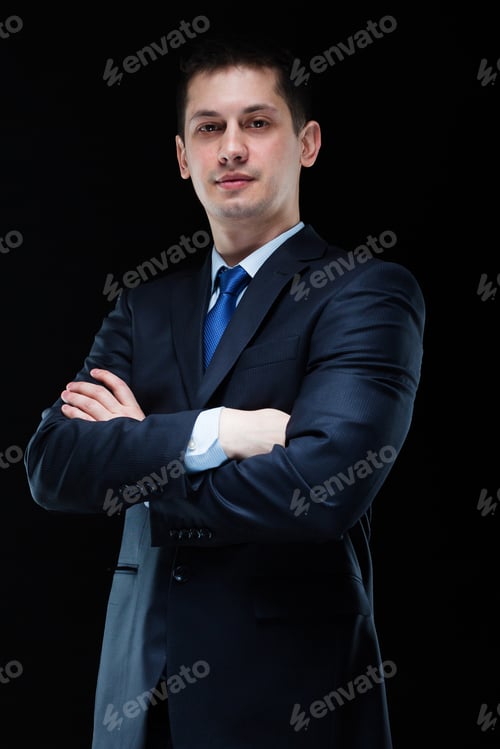 Preview: Portrait of confident handsome businessman with crossed arms on black background