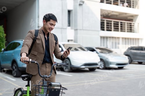 Preview: Asian businessman in a suit is riding a bicycle on the city streets for his morning commute to work