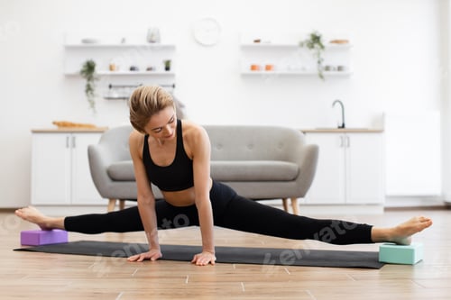 Preview: Woman practicing yoga split stretch at home on yoga mat