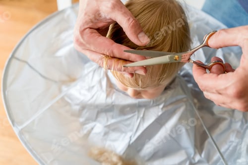 Preview: Man hands doing toddler haircut at home with hairdresser scissors