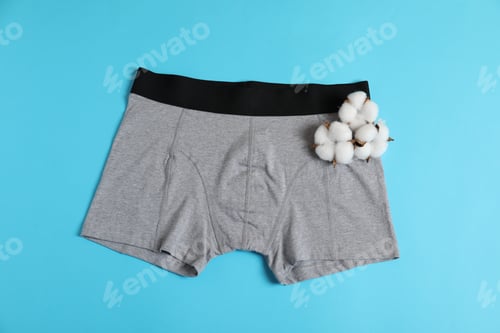 Preview: Comfortable gray men's underwear and cotton flowers on light blue background, top view