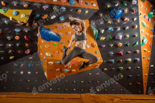 Preview: Pretty young woman jumping in climbing gym