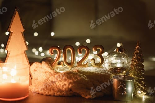 Preview: Happy New Year 2023. Number 2023 made by candles on a festive sparkling bokeh background in the dark