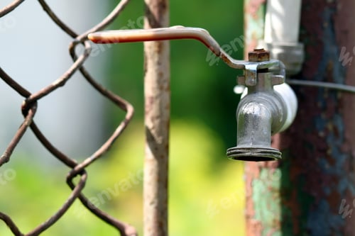 Preview: Close up of grunge brass faucet on green bokeh background. Water shortage and earth day concept