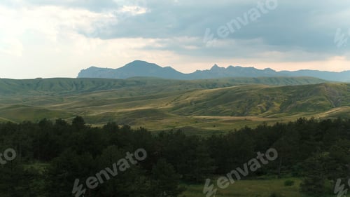 Preview: Beautiful mountain landscape with green hills and rocks on horizon. Shot. Top view of green trees on