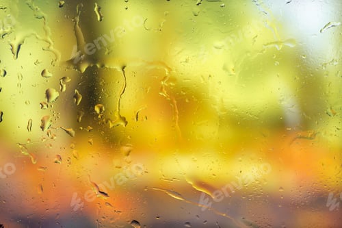 Preview: Autumn background. Drops of rain on the wet window and autumn colors of red orange and yellow