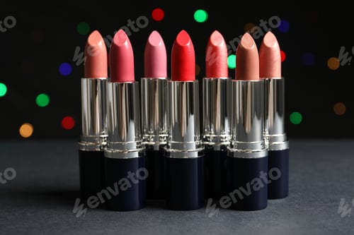 Preview: Different lipsticks on table against blurred lights. Cosmetic product