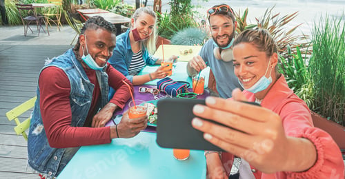 Preview: Friends taking selfie in a bar restaurant with face mask on in coronavirus time