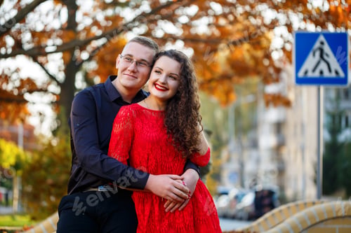 Preview: guy in a black shirt and a girl with curls in a red dress on an autumn city alley