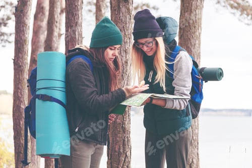 Preview: Two young tourist determine the route map and compass.