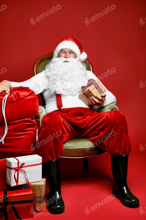 Preview: Caucasian Santa Claus sitting on the retro chair with Christmas presents