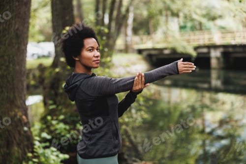Preview: Black Woman Stretching Before Running Neat The River In Nature
