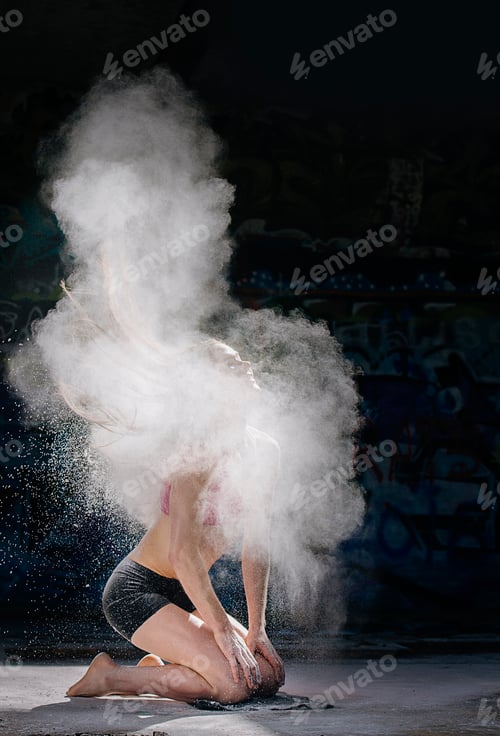 Woman kneeling throwing powder covered hair back