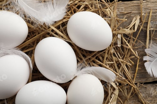 Preview: Raw chicken eggs, feathers and straw on wooden table, flat lay