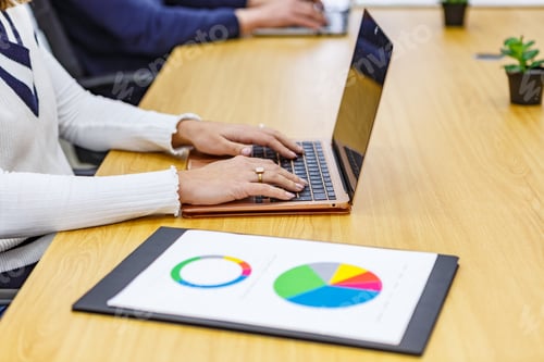 Preview: Hands typing on laptop with charts on table in coworking space