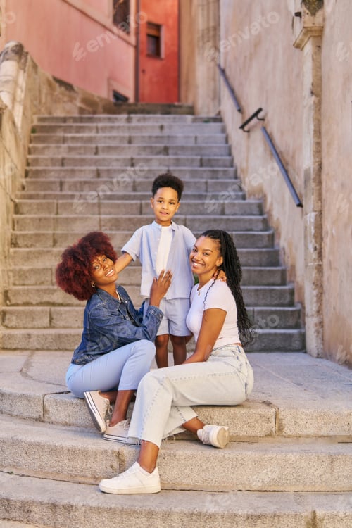 Preview: family time portrait of two women and a child sitting on some steps. looking at the camera