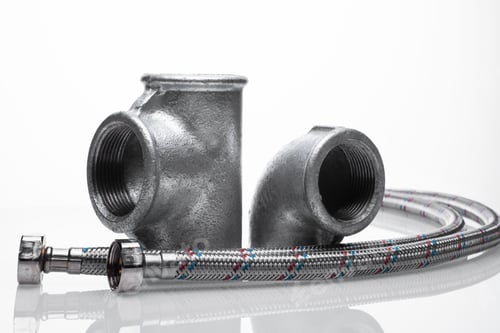 Preview: steel pipe fittings on a white background. metal tee, corner and two reinforced hoses.