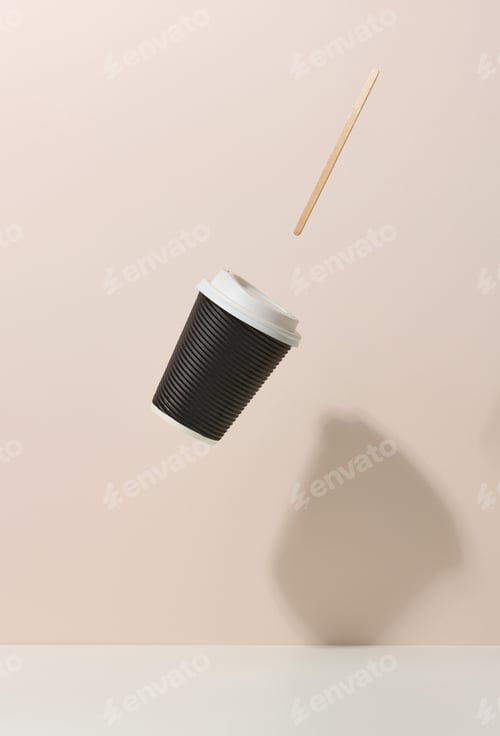 Preview: Brown cardboard cup with a white plastic lid and a wooden stirring stick levitate over a white table