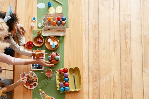 Preview: Family hands decorating colorful Easter eggs for spring holiday tradition