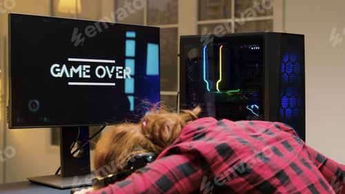 Preview: Woman with head on desk after losing a gaming competition