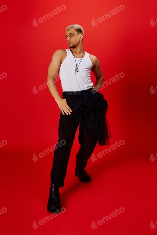 Preview: Young man with stylish dyed hair poses confidently in a vibrant red studio setting