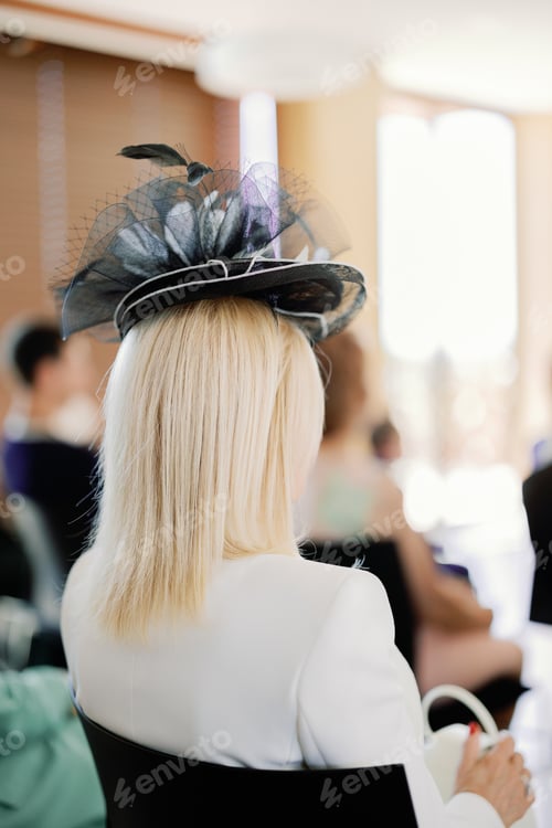 Preview: blonde woman from behind wearing a feathered hat