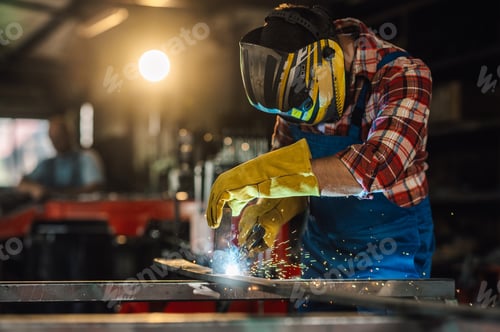 Preview: Skilled man welding a metal construction while wearing a safety gear.