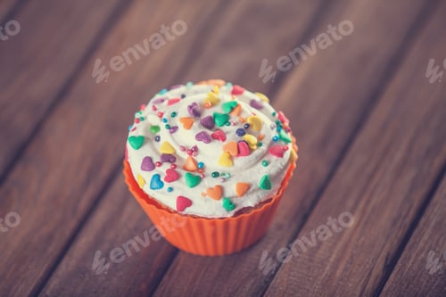Preview: Cupcake and bow on wooden table.