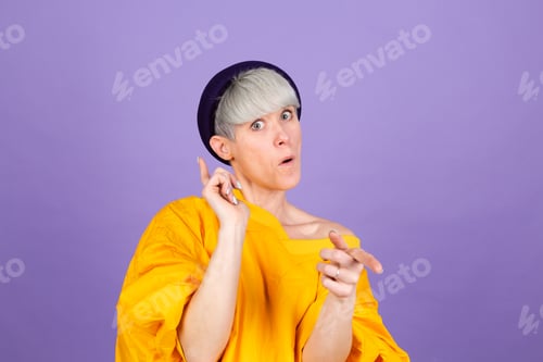 Preview: Stylish european woman on purple background point to you to camera with happy face