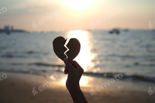 Preview: hand holding broken heart shape with sunset background, silhouette valentines background.