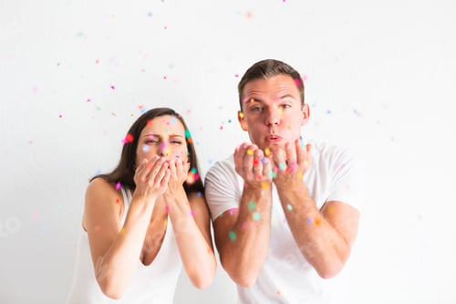 Preview: Young man and woman blowing confetti decorations
