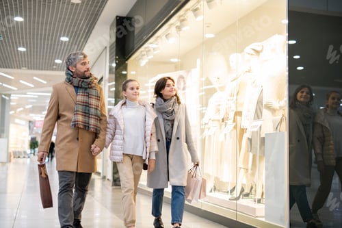 Preview: Happy parents and daughter looking at new casualwear collection in shop window