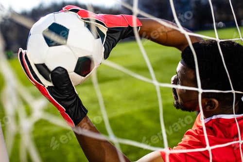Preview: brazilian man goalkeeper catches the ball in the stadium during a football training
