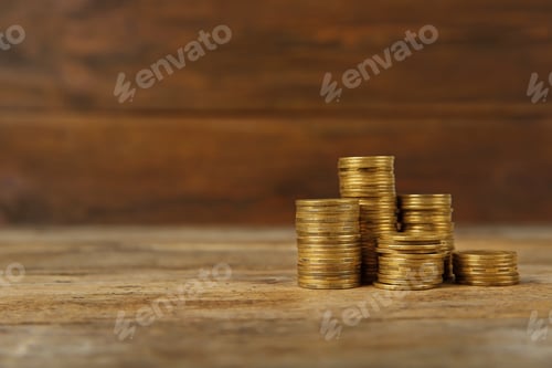 Preview: Stacks of Golden Coins on a Wooden Surface